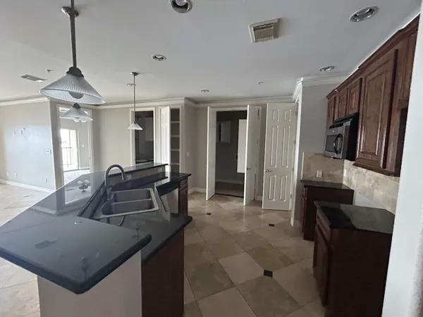 a kitchen with granite countertop a sink a counter top space and stainless steel appliances