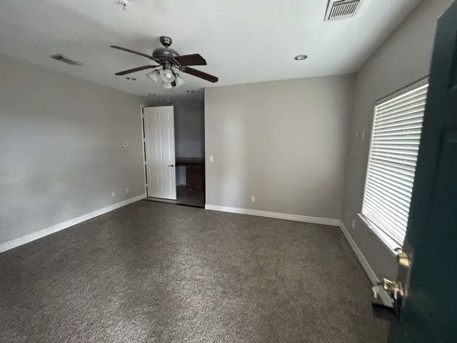 an empty room with a ceiling fan and window