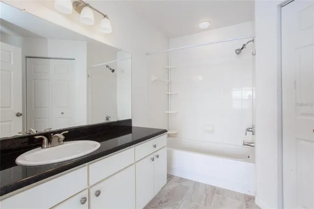 a bathroom with a granite countertop sink a mirror a bathtub and shower