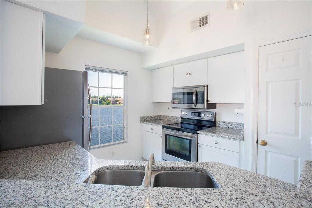9704 Lake Chase Island Way, Unit 9704 Tampa, FL 33626 - Photo 5 of 23 a kitchen with stainless steel appliances granite countertop a sink stove and refrigerator