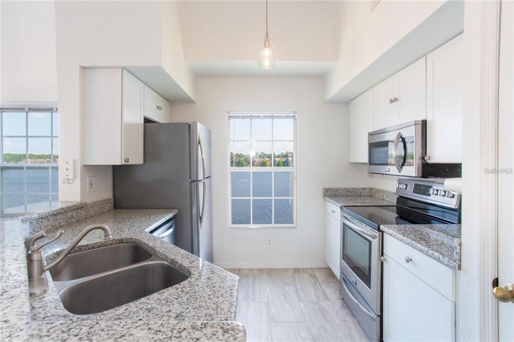 9704 Lake Chase Island Way, Unit 9704 Tampa, FL 33626 - Photo 6 of 23 a kitchen with stainless steel appliances granite countertop a sink stove and refrigerator