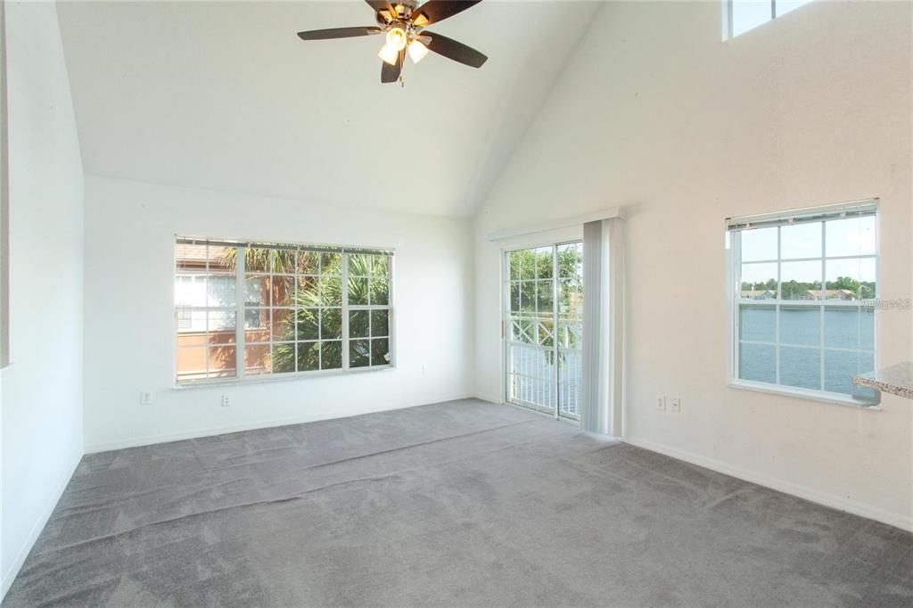 9704 Lake Chase Island Way, Unit 9704 Tampa, FL 33626 - Photo 8 of 23 an empty room with chandelier fan and windows