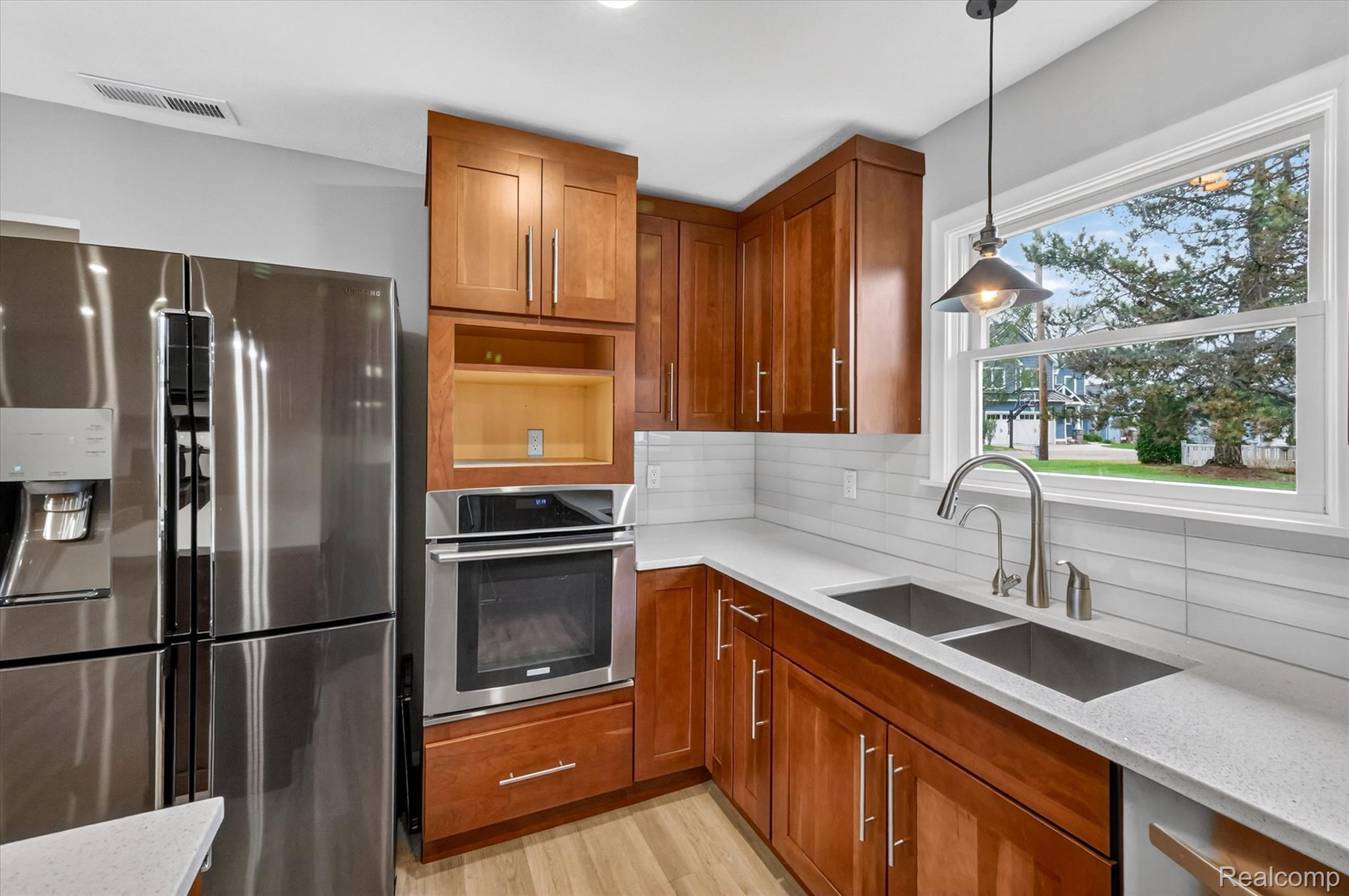 2264 Crane Road Fenton, MI 48430 - Photo 17 of 55 Kitchen with stainless steel appliances, wood finish cabinetry, light stone countertops, and decorative light fixtures