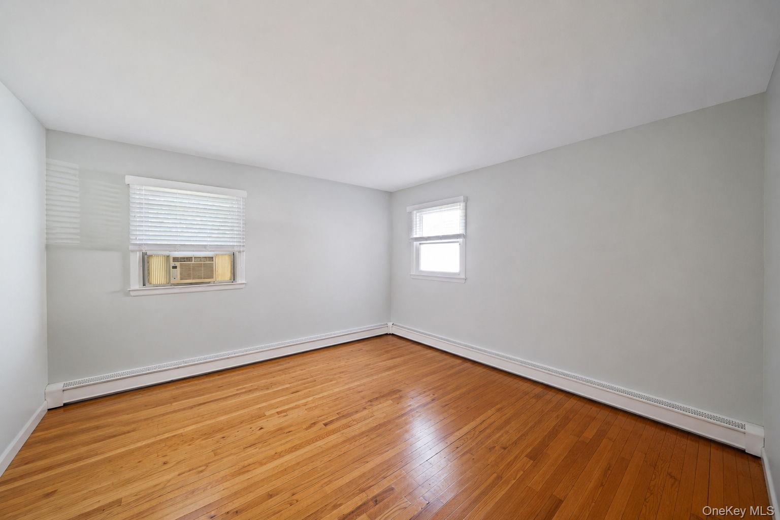 31 Crooked Hill Road Huntington, NY 11743 - Photo 12 of 32 Interior space featuring wood-finish flooring, two window openings, and baseboard heating elements