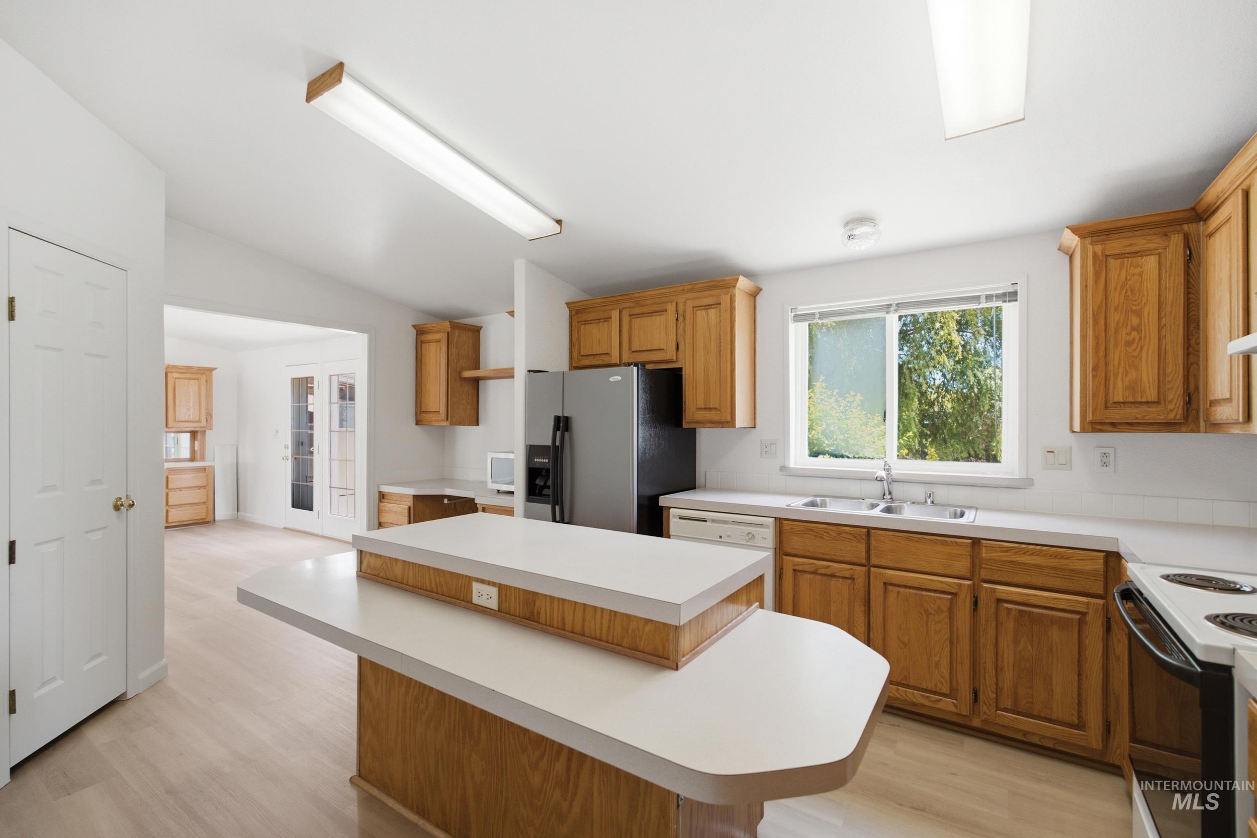 7422 Track Road Nampa, ID 83686 - Photo 7 of 50 Kitchen featuring wood-finish cabinetry, light-toned countertops, and an integrated kitchen island with a breakfast bar