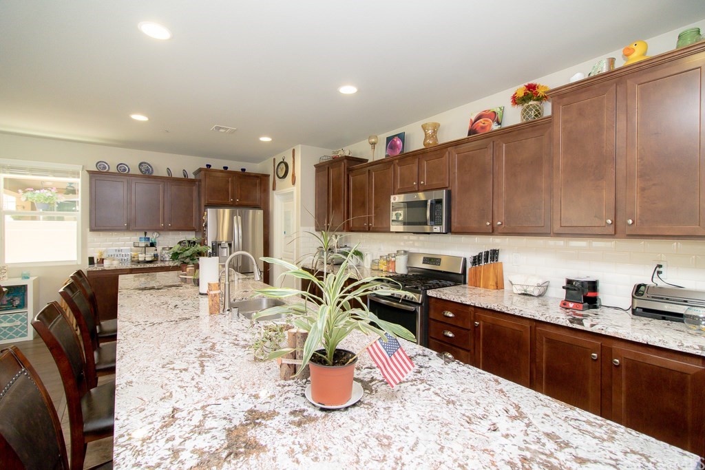 35251 Smith Avenue Beaumont, CA 92223 - Photo 10 of 33 a kitchen with stainless steel appliances kitchen island granite countertop a sink dishwasher stove top oven and cabinets