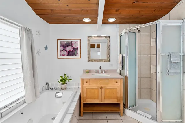 a bathroom with a tub a sink and glass door shower