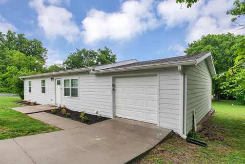 a backyard of a house with plants and barbeque oven
