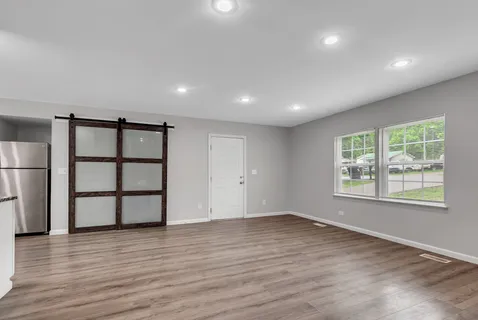 an empty room with wooden floor and windows