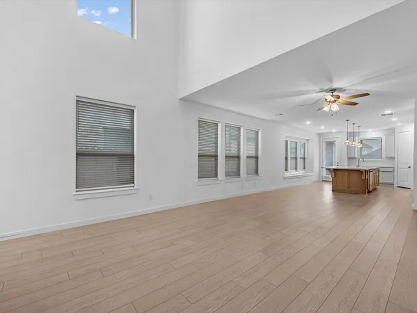 a view of empty room with wooden floor and kitchen view