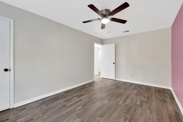 an empty room with wooden floor and ceiling fan