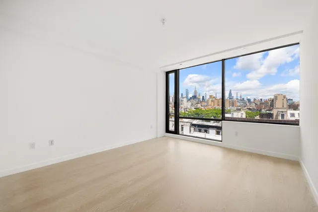 an empty room with wooden floor and a large window