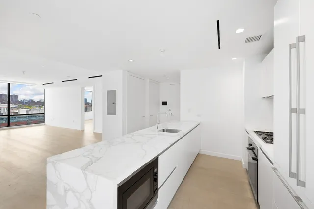 a large white kitchen with a sink a large mirror and a refrigerator