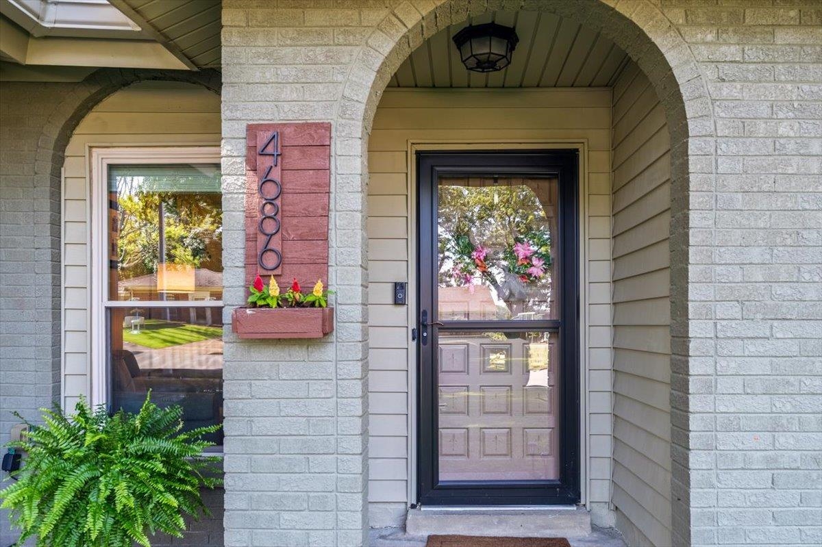 Front entry featuring a brick archway, siding exterior, and a glass storm door