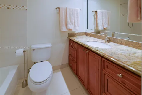 a bathroom with a granite countertop toilet sink and mirror
