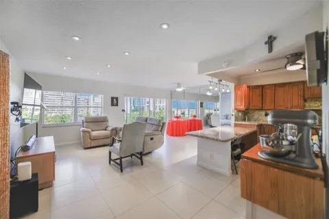 a living room with stainless steel appliances kitchen island granite countertop a table and chairs in it