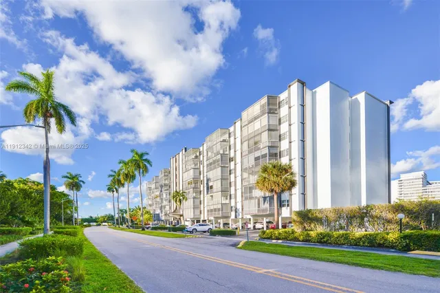 a view of a multi story residential apartment building with yard and green space