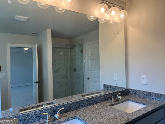 a bathroom with a granite countertop sink a mirror and a shower