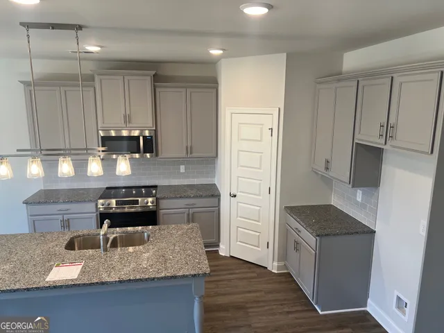 a kitchen with granite countertop a sink stove and refrigerator