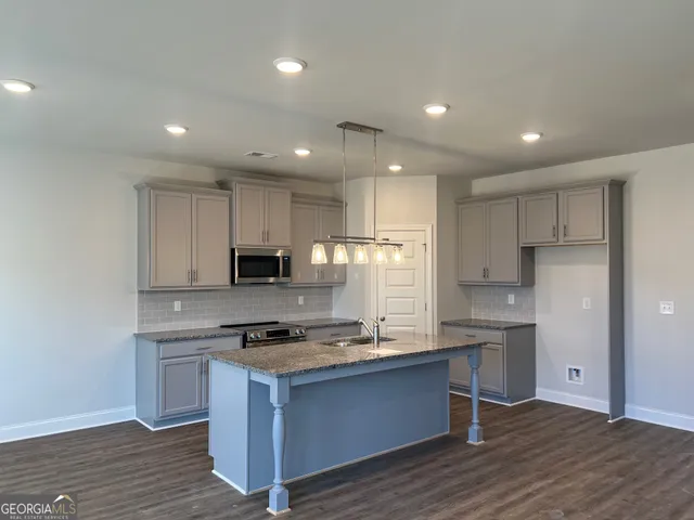 a kitchen with kitchen island granite countertop a sink and a stove top oven