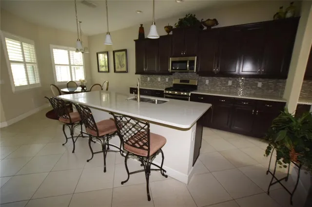 a kitchen with stainless steel appliances a sink a stove a table and chairs