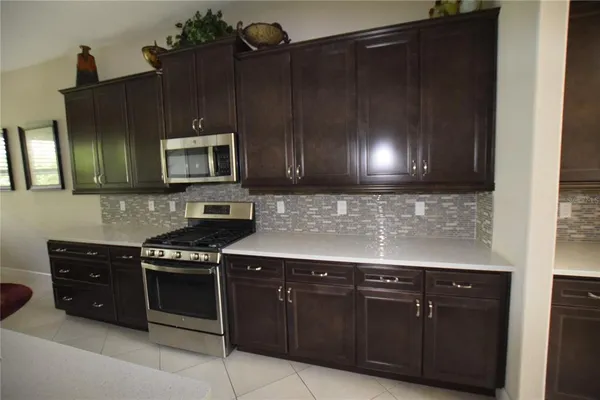 a kitchen with granite countertop a stove a microwave cabinets and a sink