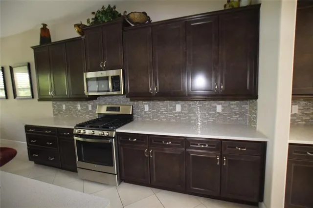 a kitchen with granite countertop a stove a microwave cabinets and a sink