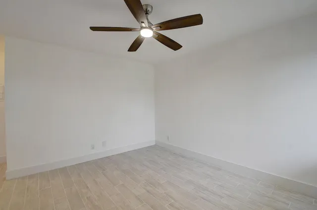 an empty room with a ceiling fan and wooden floor