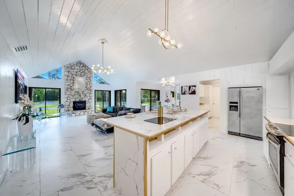 a large kitchen with kitchen island a large counter space a sink appliances and a living room view