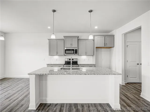a kitchen with kitchen island granite countertop a sink cabinets and stainless steel appliances