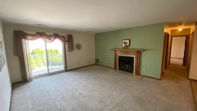 an empty room with windows and fireplace