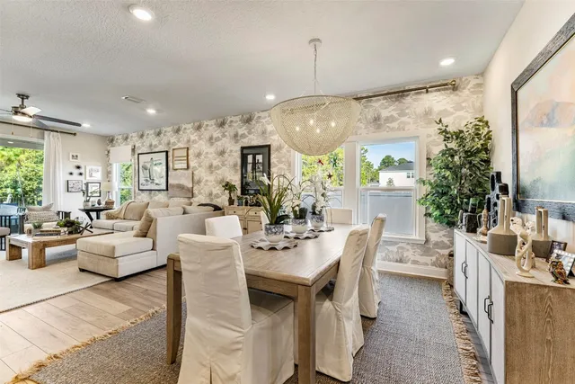 a view of a dining room and livingroom with furniture wooden floor a chandelier