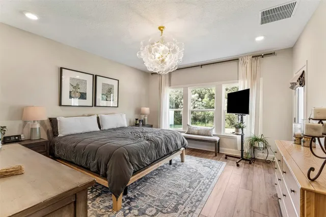 a spacious bedroom with a large bed and a chandelier
