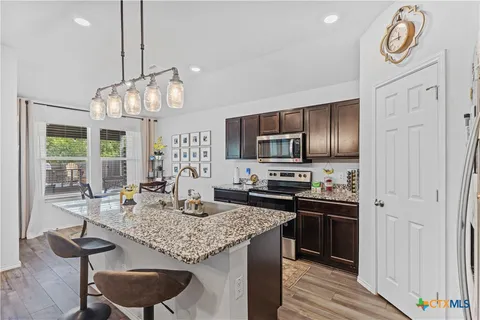 a kitchen with kitchen island granite countertop a sink cabinets and stainless steel appliances