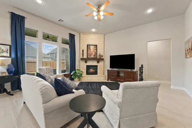 a kitchen with stainless steel appliances granite countertop a sink a refrigerator a stove a kitchen island with chairs and white cabinets