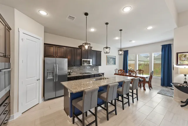 a kitchen with stainless steel appliances granite countertop a sink a stove and a refrigerator