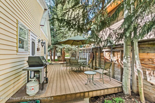 a view of a patio with table and chairs with wooden floor and fence