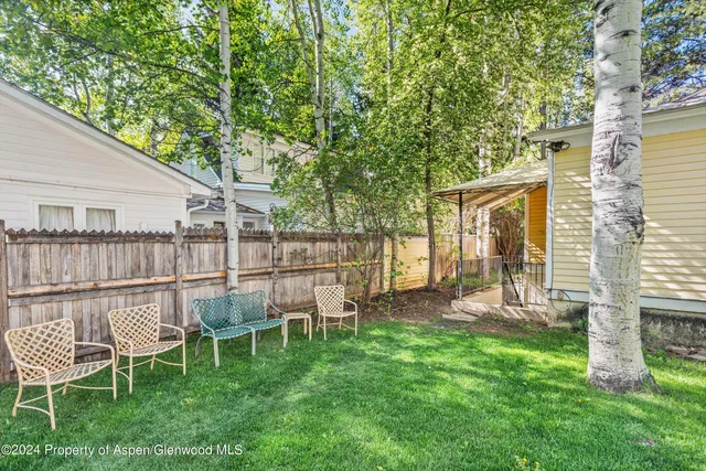 a view of a chair and table in backyard of the house
