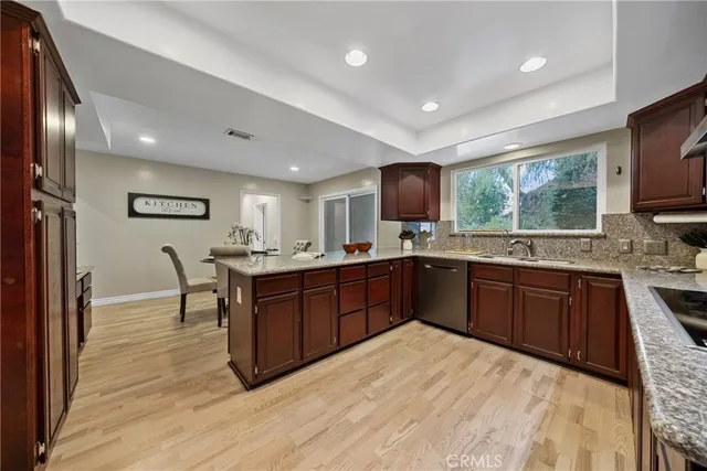 a kitchen with stainless steel appliances granite countertop a refrigerator a sink dishwasher a stove with wooden cabinets and floor