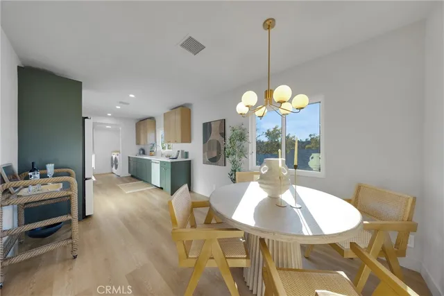 a living room with couches chandelier and a dining table with wooden floor