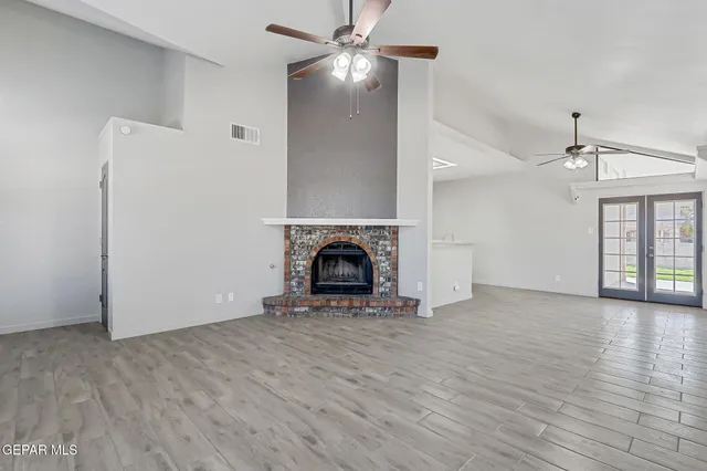 a view of empty room with wooden floor fireplace and fan