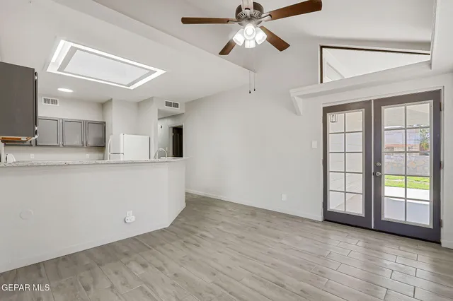 an empty room with wooden floor cabinet and a ceiling fan