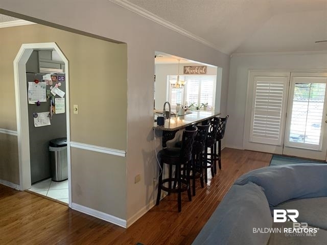 23393 Miflin Road Foley, AL 36535 - Photo 8 of 12 Dining room featuring baseboards, vaulted ceiling, ornamental molding, an inviting chandelier, and wood finished floors