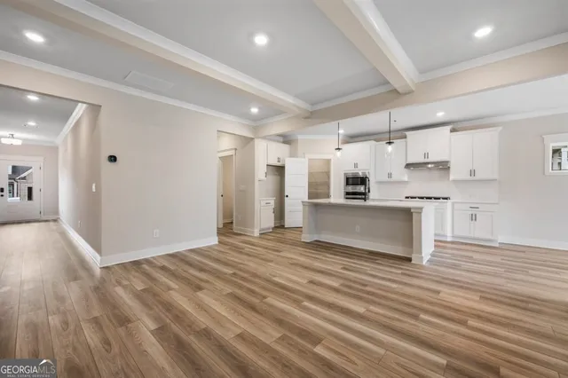a view of a kitchen with kitchen island a sink wooden floor and a refrigerator