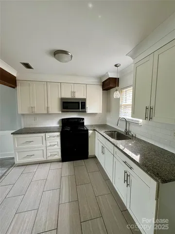 a large kitchen with stainless steel appliances granite countertop a stove a sink and a granite counter tops