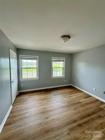a view of an empty room with window and wooden floor