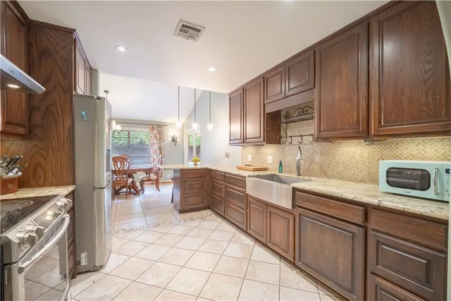 a kitchen with granite countertop a refrigerator stove and cabinets