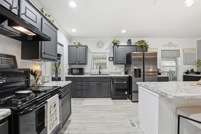 a kitchen with stainless steel appliances granite countertop a stove top oven a sink dishwasher and a refrigerator