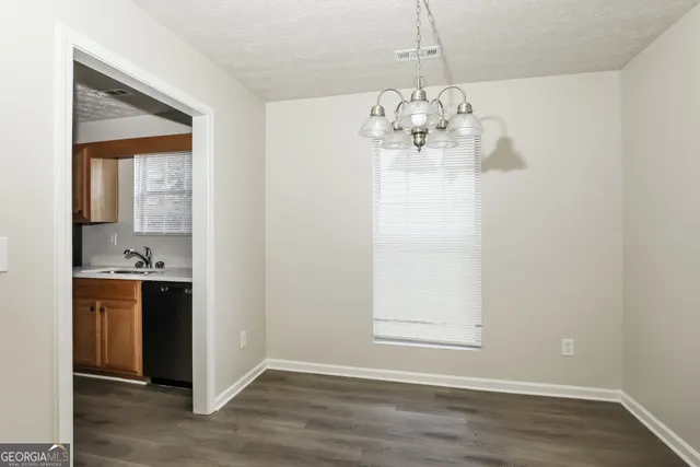 a view of an empty room with kitchen and stove