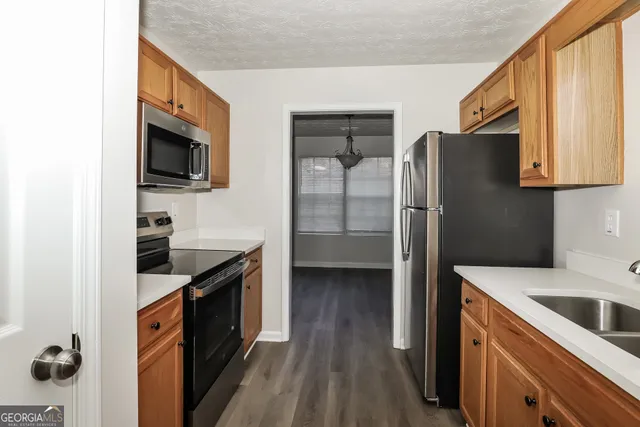 a kitchen with stainless steel appliances granite countertop a refrigerator a stove and a sink with wooden floor